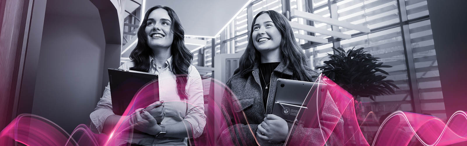 Image of two girls holding books walking in a building