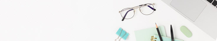 a laptop, glasses and stationery on a plain background