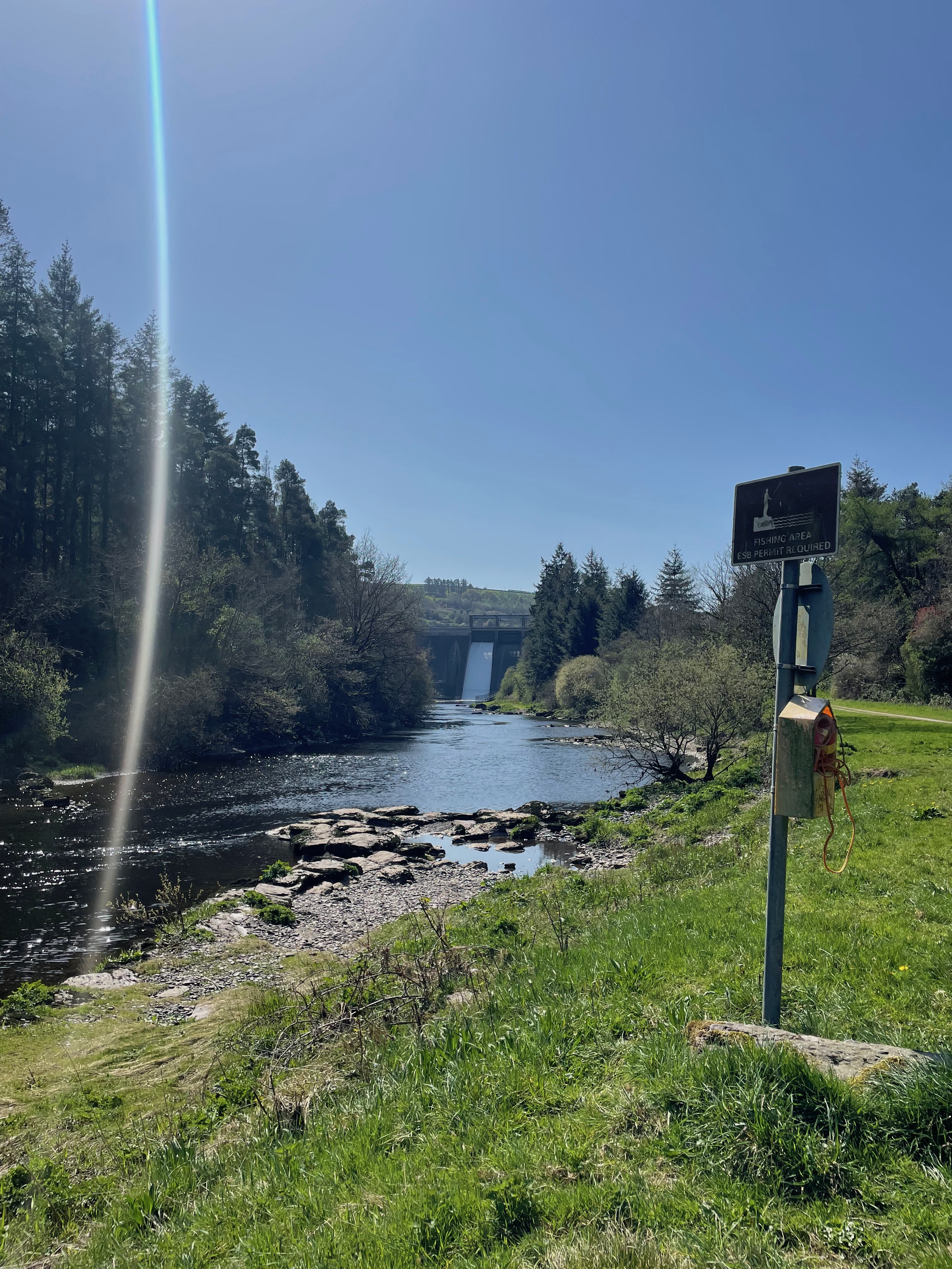 Picture of the River Lee below the Iniscarra Dam in County Cork. Framed by trees and a sign that reads 