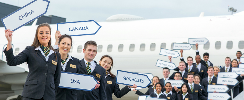 Students wearing uniforms smiling holding signs representing countries around the world