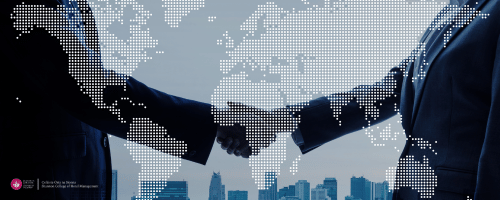two people shaking hands in business suits with a globe background