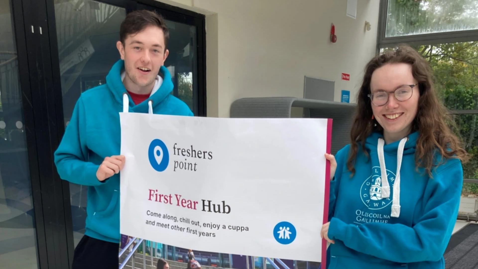 two freshers' point facilitators holding a poster about the event