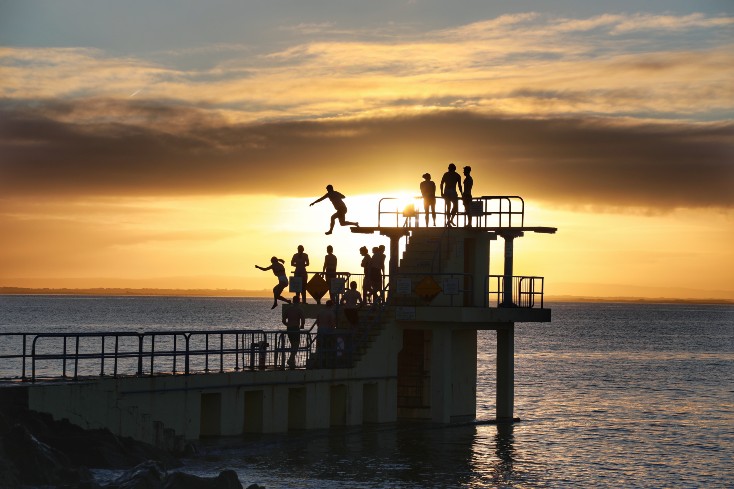 people diving at Blackrock diving tower at sunset
