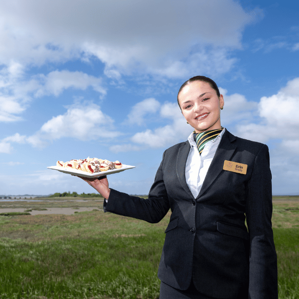 Year 3 student in her uniform holding a tray of desserts 